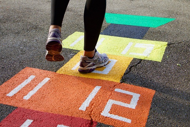 Young person playing hopscotch on a rainbow coloured pitch