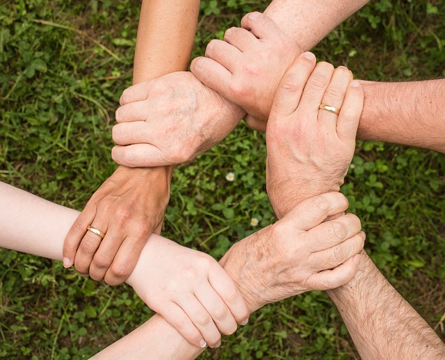 Several hands holding together to form a circle to represent teamwork